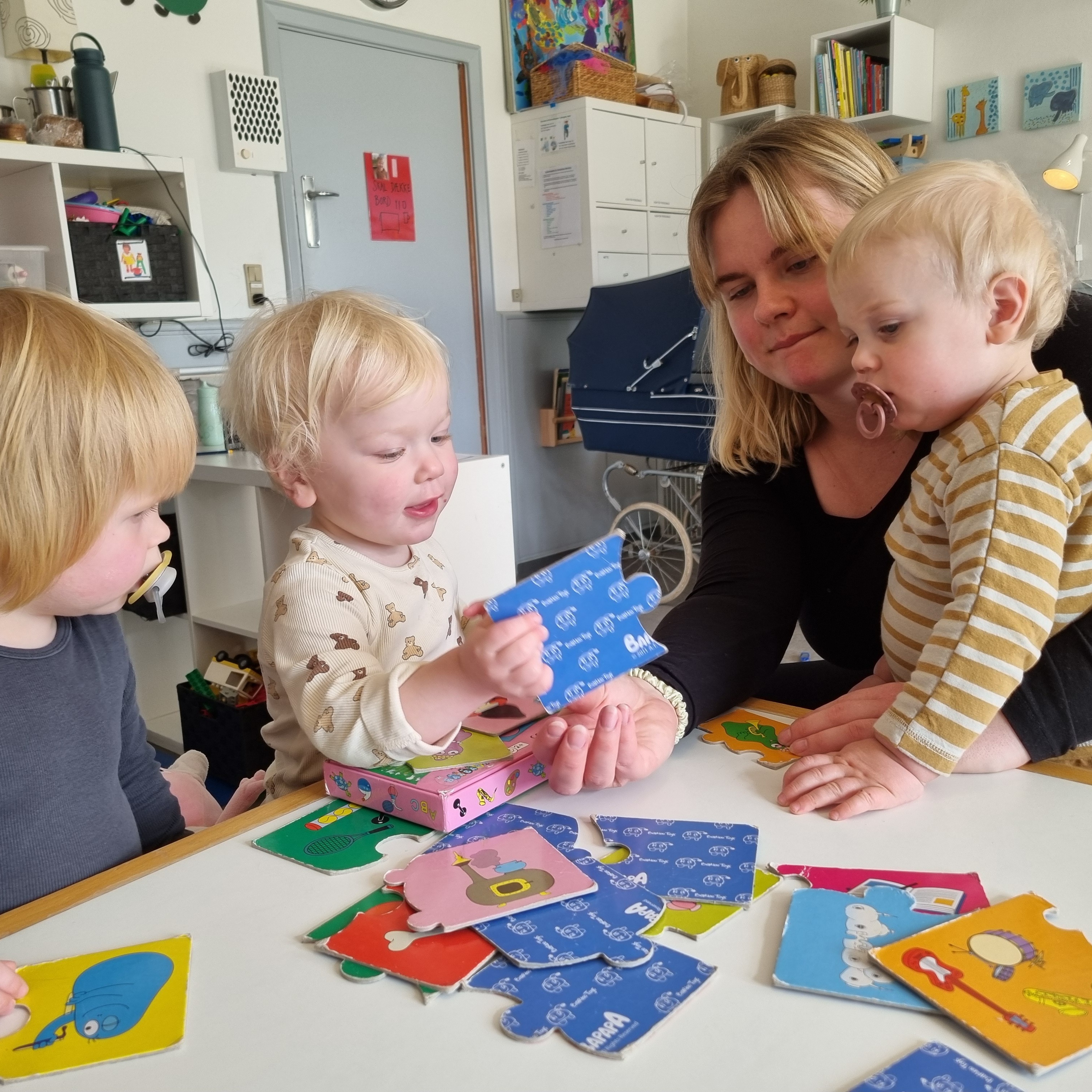 Vuggestuebørn hygger med spil sammen med en voksen.